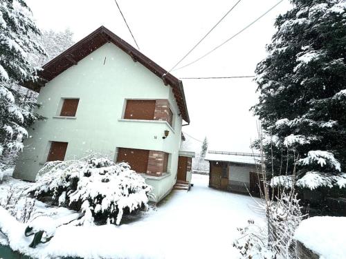 a house covered in snow with trees in front of it at Gîte de Pipala in Mittlach