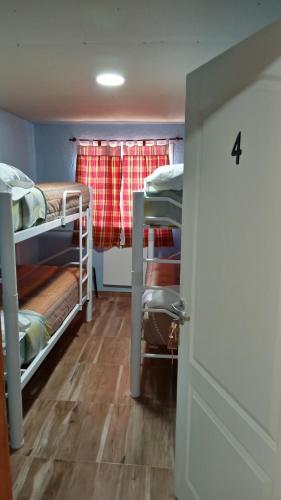 Zimmer mit 4 Etagenbetten und einer Tür in der Unterkunft Los Milenarios in El Chalten