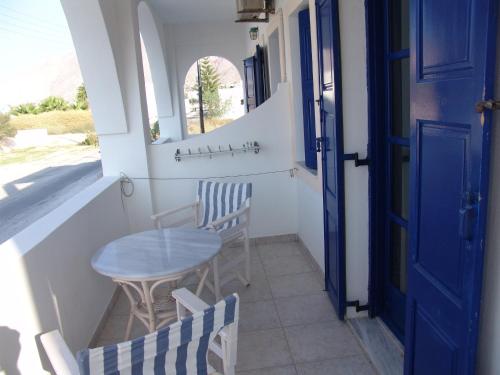 a small table and chairs on a balcony with a blue door at Villa Nefeli in Perissa