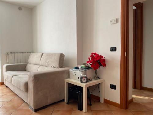 a living room with a couch and a table with flowers at Colleoni Apartment di Manenti Andrea in Oltre il Colle
