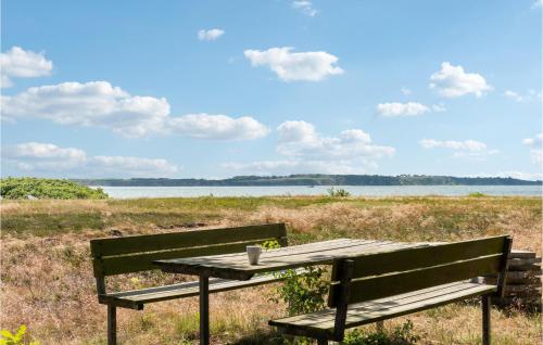 a picnic table with a cup on it sitting next to a lake at Strandbo in Thyholm