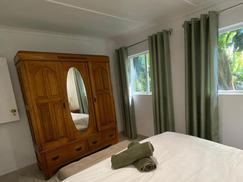 een slaapkamer met een groot bed met een spiegel en een dressoir bij Birdsong Cottage in Swellendam