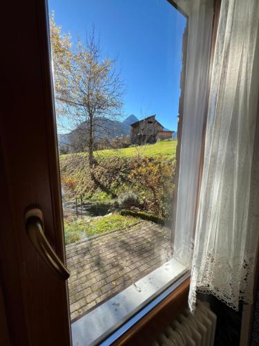 a window with a view of a field and a house at Da Bino - Vicino Pista Ciclabile in Valle di Cadore