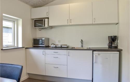 a kitchen with white cabinets and a sink and a microwave at Holiday Home Halvejen Hytte Spjald Ii in Spjald