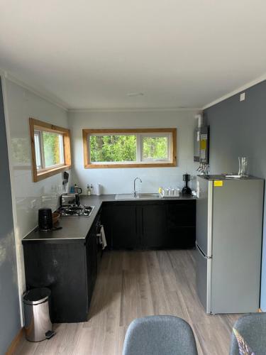 a kitchen with black cabinets and a white refrigerator at Cabañas Entre Sauces in Coihaique