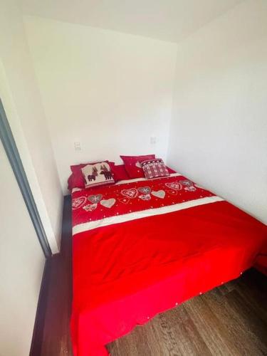 - un lit rouge avec des draps et des oreillers rouges dans l'établissement Serre Chevalier Chantemerle Vue Montagne, à Saint-Chaffrey