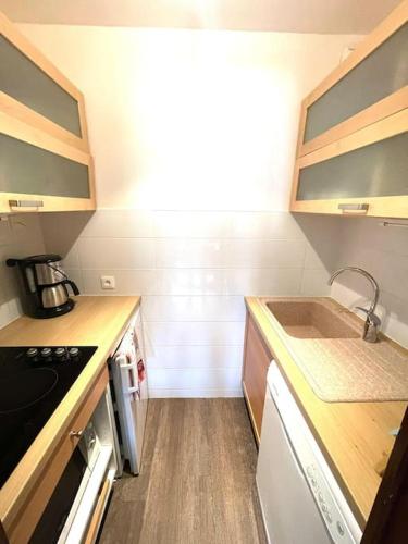 une petite cuisine avec un évier et une cuisinière dans l'établissement Serre Chevalier Chantemerle Vue Montagne, à Saint-Chaffrey