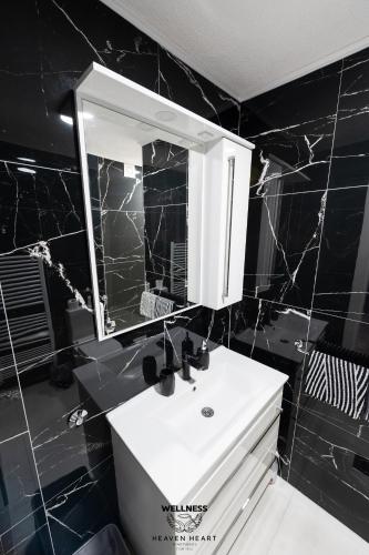 a bathroom with a white sink and a mirror at Heaven Heart - Apartmani Tuzla in Tuzla
