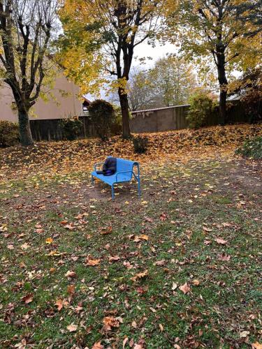 a blue bench sitting in the grass in a yard at Champions Deluxe in Sarcelles