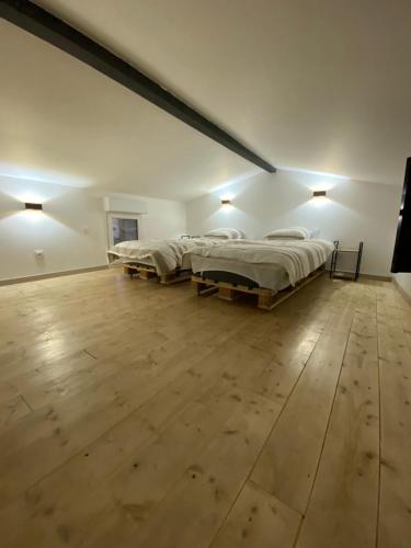 a large white room with two beds and a wooden floor at Gîte berclois in Bercloux