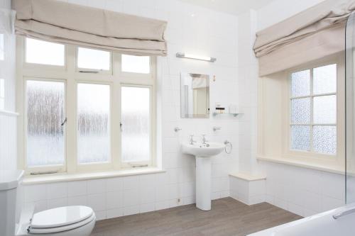 a white bathroom with a toilet and a sink at The Bell Hotel in Sandwich