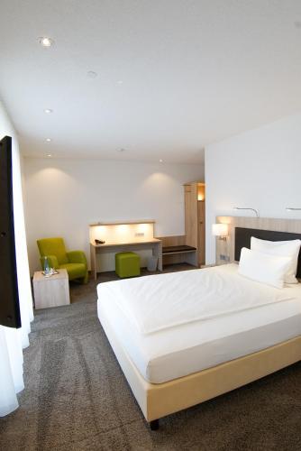 una camera da letto con un grande letto bianco e sedie verdi di Hotel Go2Bed Weil am Rhein - Basel a Weil am Rhein