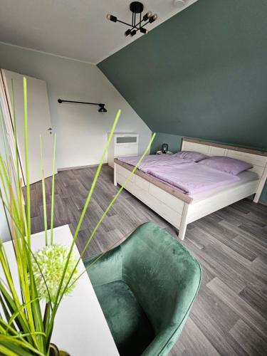 a bedroom with a bed and a green chair at Stilvoll eingerichtetes Ferienhaus in ruhiger Lage in Bremerhaven