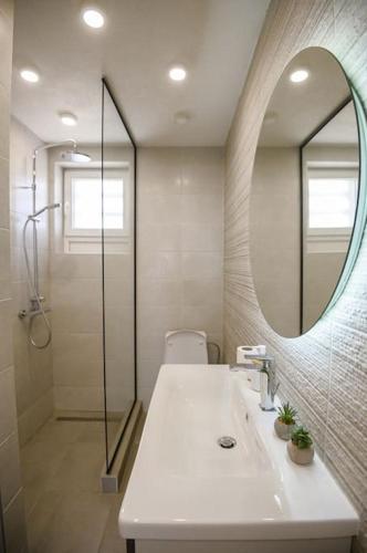 łazienka z umywalką, lustrem i prysznicem w obiekcie 4U Apartment w mieście Skopje