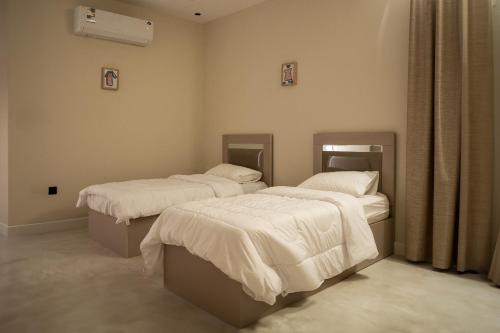 a room with two beds with white comforters at Elite Family in Al Madinah