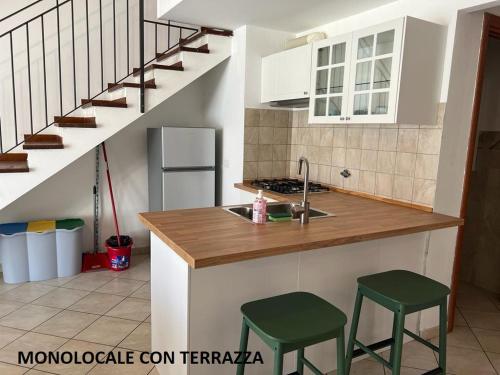 una cocina con fregadero y 2 taburetes verdes en Appartamenti Sofia a Marina di Cecina 100m dal mare, en Marina di Cecina