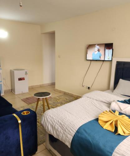 a hotel room with two beds and a tv on the wall at Kiserian Comfort in Kiserian