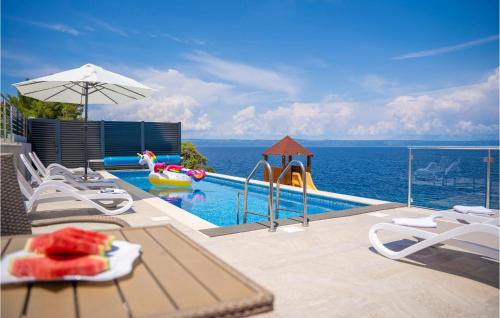 a pool with a table and chairs and the ocean at Awesome Home In Crnja Luka With Kitchen in Prigradica