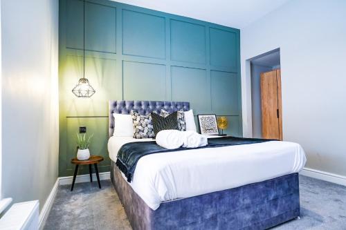 a bedroom with a large bed with a blue wall at Studio 44 - Spacious Studios - City Centre Location - Contractor Friendly - Free WiFi - Smart TV - Desk Space - Well Designed - Communal Garden in Peterborough