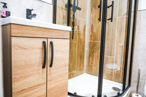 a bathroom with a shower and a wooden cabinet with a sink at Studio 44 - Spacious Studios - City Centre Location - Contractor Friendly - Free WiFi - Smart TV - Desk Space - Well Designed - Communal Garden in Peterborough
