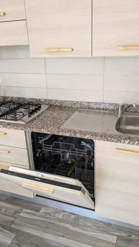 an empty dishwasher in a kitchen next to a sink at Mazzini Green Suites Jesolo in Lido di Jesolo
