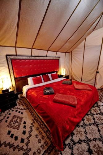 a bedroom with a red bed in a tent at Hamada Activities Luxury Camp in Merzouga