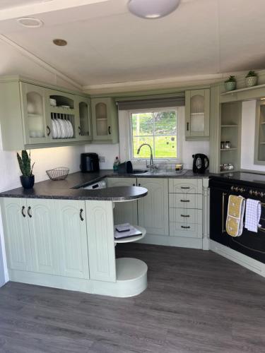a kitchen with white cabinets and a sink at The Vogue Lodge in Buxton