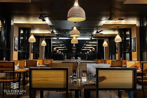 a restaurant with wooden tables and chairs and lights at Tea Terrain Resorts & Spa in Vagamon