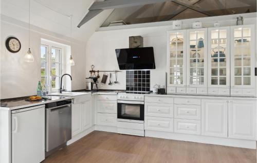 a white kitchen with white cabinets and a tv at Stunning Home In Ålbæk With Kitchen in Ålbæk