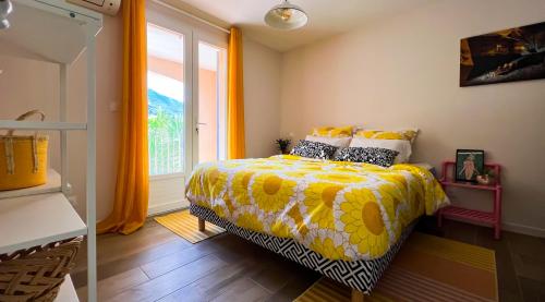 a bedroom with a bed with a yellow comforter and a window at Maison LeFleur - Villa avec piscine sur les hauteurs de Nice in Nice