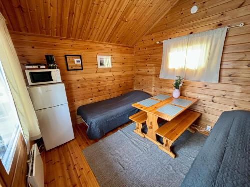 Zimmer mit einem Tisch und einem Bett in einer Hütte in der Unterkunft Vuohimäki Camping Savonlinna in Savonlinna