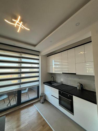 a kitchen with white cabinets and a large window at Zlatiborske terase Spa&Wellness in Zlatibor