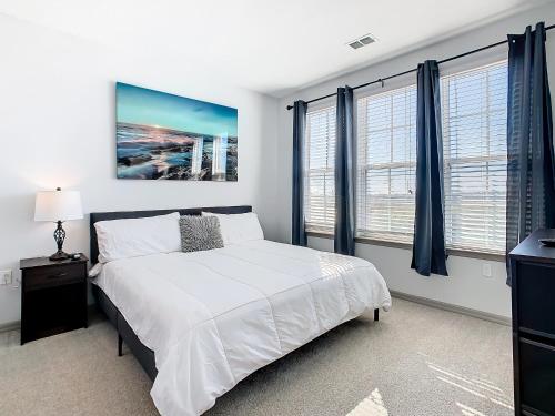 a bedroom with a large bed and two windows at Your Dream Apartment Stay in Kissimmee