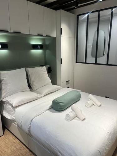 - un grand lit avec un oreiller vert et des oreillers blancs dans l'établissement Magnifique appartement Le Marais Paris, à Paris