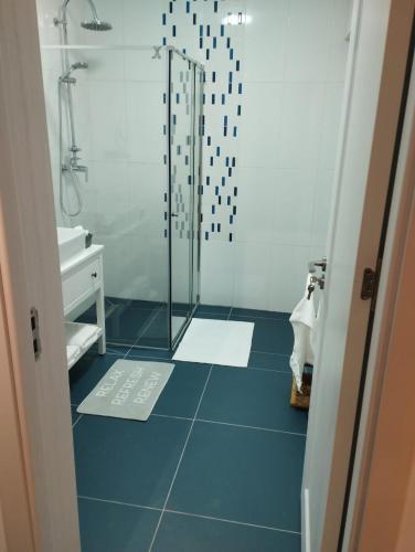 a bathroom with a shower and a blue tile floor at Ady s vision luxury apartment in Şelimbăr