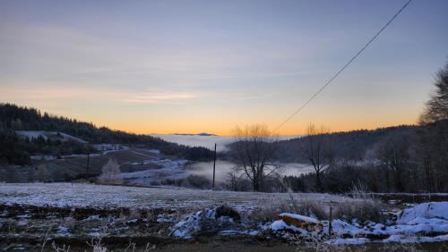 a view of a snowy field with the sun setting in the background at Kuća sa lepim pogledom - porodica Čolović in Rudno