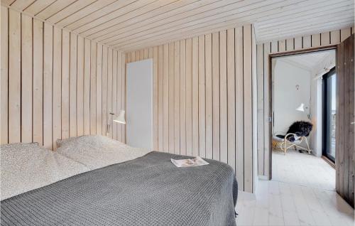 a bedroom with a bed and a wooden wall at 3 Bedroom Stunning Home In Thyholm in Thyholm