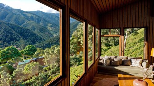 a living room with a couch and a large window at Lauraceas Lodge in San Gerardo de Dota