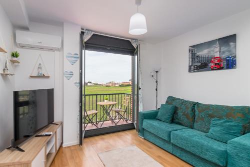 a living room with a green couch and a balcony at Suances mar y tierra con parking in Suances