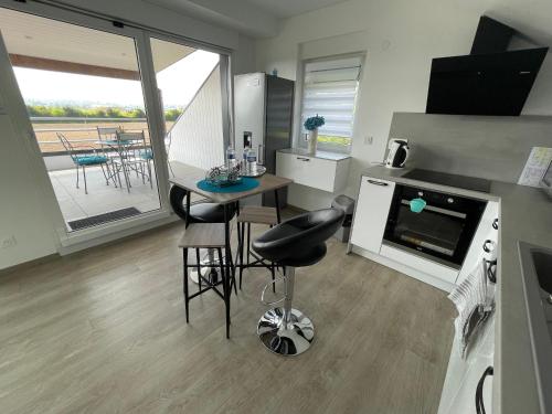 Il comprend une cuisine équipée d'une cuisinière et d'une table avec un comptoir. dans l'établissement Loft Bellevue, à Saint-Louis