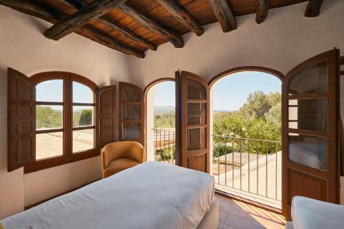 a bedroom with a bed and a balcony with windows at The Guardian House in Santa Gertrudis de Fruitera