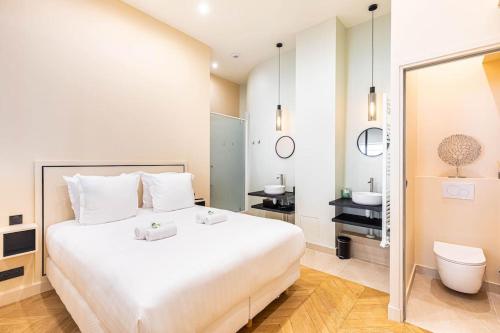 une chambre avec un grand lit blanc et une salle de bain dans l'établissement comme une maison - Invalides-Musée Rodin, à Paris