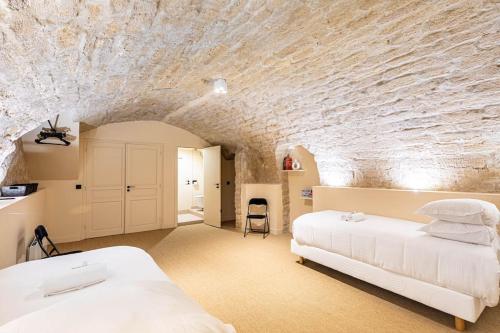 une chambre avec un lit blanc et un mur en pierre dans l'établissement comme une maison - Invalides-Musée Rodin, à Paris