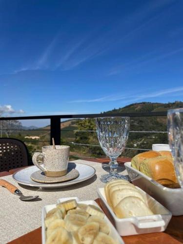 a table with bread and a cup of coffee and glasses at Chalé da Pedra in Pedra Menina