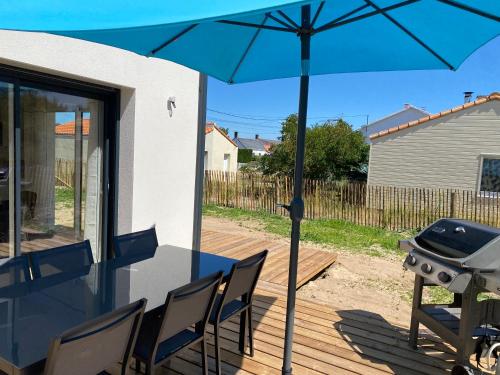 d'une terrasse avec un grill et un parasol bleu. dans l'établissement Maison neuve entre mer et forêt, à Saint-Jean-de-Monts