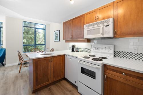 a kitchen with a white stove and a microwave at Alpenglow Lodge Bear Wonder One Bedroom by MVA in Whistler