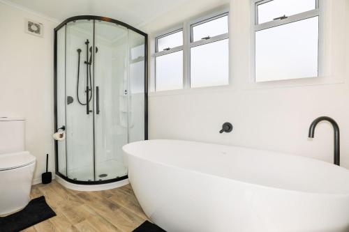 ein weißes Badezimmer mit Badewanne und Dusche in der Unterkunft Lake views in great area in Taupo
