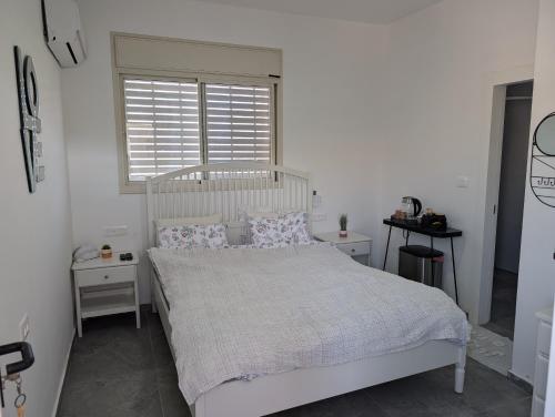 a bedroom with a white bed with pillows and a window at Dardar suite יחידת אירוח בבאר אורה in Beʼer Ora