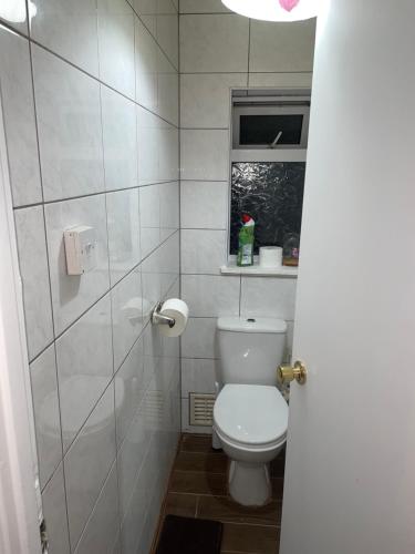 a white bathroom with a toilet and a window at Family-friendly home in London in London
