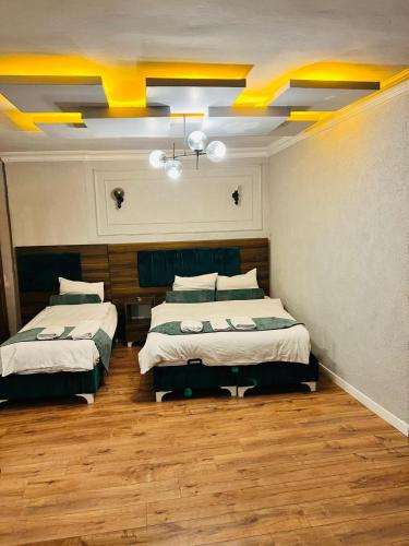 two beds in a room with yellow ceilings and wood floors at Pembe Köşk Old City Center in Istanbul